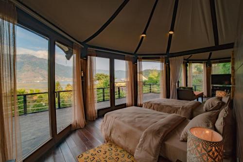 a bedroom with two beds and a balcony with windows at The Pavilions Himalayas Lake View in Pokhara