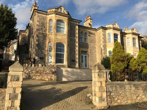 a large house with a stone fence in front of it at Cannon House in Weston-super-Mare