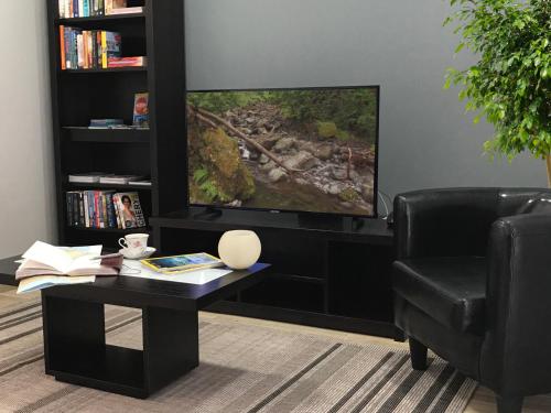 a living room with a tv and a table and a chair at Lucilia's House in Calheta
