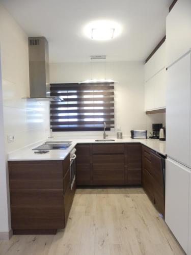 a large kitchen with wooden cabinets and a sink at Beachside Jablillo y Cucharas in Costa Teguise