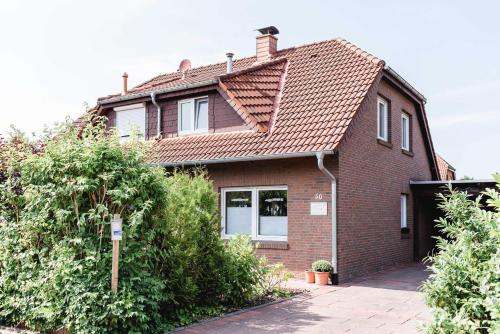 una casa de ladrillo rojo con techo de baldosa en Haus am Teich, en Hooksiel