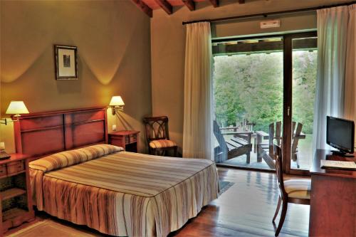 a bedroom with a bed and a television and a balcony at Palación de Toñanes in Toñanes