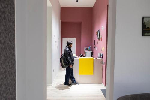un hombre está parado en un mostrador en una habitación rosa en Travel Inn Hostel, en Baku