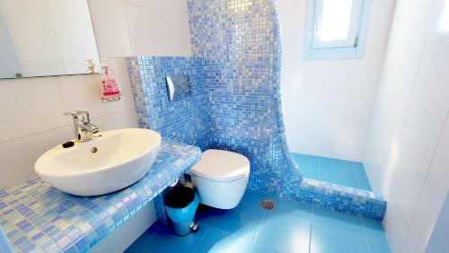 ein blau gefliestes Badezimmer mit Waschbecken und Toilette in der Unterkunft Artemis Village in Karterados