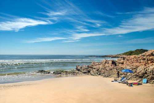 a person sitting on a beach near the ocean at The Plettenberg Hotel in Plettenberg Bay