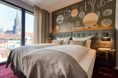 a bedroom with a large bed and a large window at Centro Hotel Stern Ulm City, Trademark Collection by Wyndham in Ulm