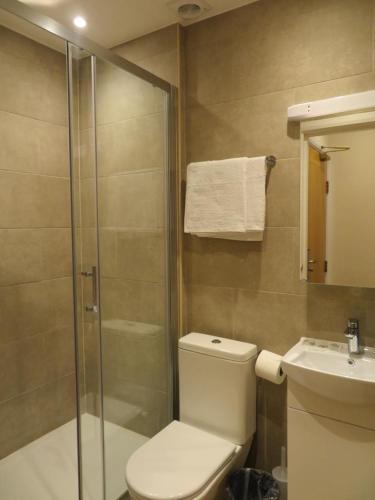 a bathroom with a shower and a toilet and a sink at Glendale Hyde Park Hotel in London