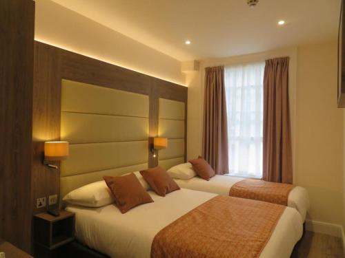 a hotel room with two beds and a window at Glendale Hyde Park Hotel in London