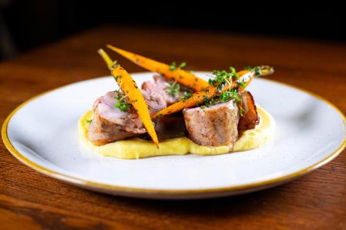 a plate of food with meat and carrots on a table at Hotel Oya in Prague