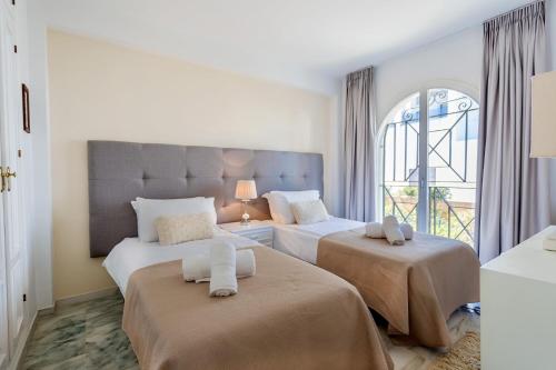 een slaapkamer met 2 bedden en een groot raam bij Beach View Playa Del Moral in Estepona