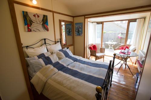 a bedroom with a bed with blue and white striped sheets at Heatherbell Cottage Guest Accommodation in West Bay