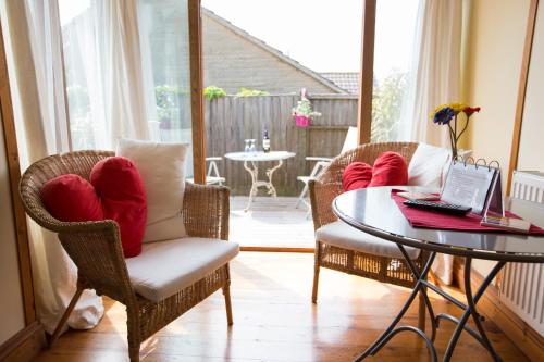 ein Wohnzimmer mit Stühlen und einem Tisch mit einem Laptop in der Unterkunft Heatherbell Cottage Guest Accommodation in West Bay