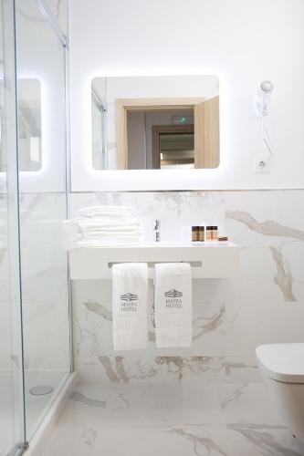 a white bathroom with a sink and a mirror at Mafra Hotel in Mafra