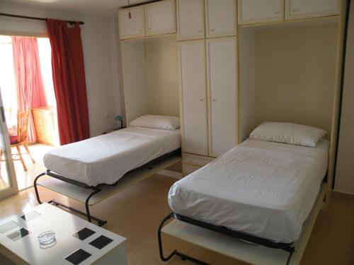 two beds in a small room with a table and a room at Ducado - Fincas Arena in Benidorm
