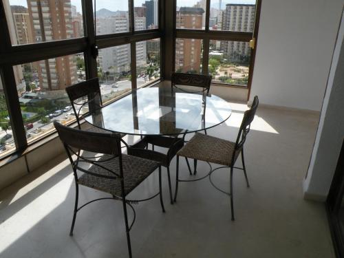 a glass table and chairs in a room with windows at Gemelos 2 II - Fincas Arena in Benidorm
