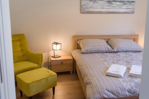 ein Schlafzimmer mit einem Bett und einem gelben Stuhl in der Unterkunft Go2Krynica - Cicha in Krynica-Zdrój