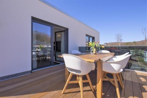 um deque com uma mesa de madeira e cadeiras brancas em Südstrandquartier - Ferienwohnung Loft em Ostseebad Sellin