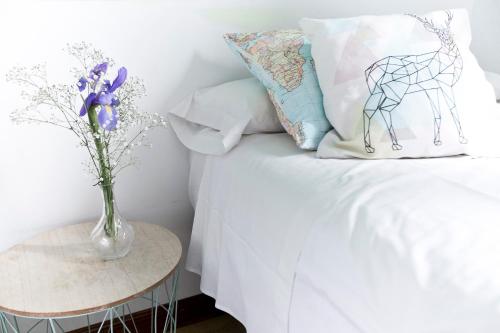 ein weißes Bett mit einer Vase aus Blumen und einem Tisch in der Unterkunft Vázquez de Mella Gran Vía in Madrid