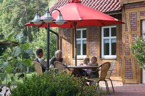 a group of people sitting at a table under a red umbrella at Ferienhof Wroge in Wietzendorf