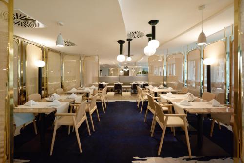 シフィノウイシチェにあるBaltic Park Molo Apartments by Zdrojowaの白いテーブルと椅子、窓のあるレストラン