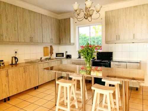 a kitchen with wooden cabinets and a large island with stools at 12 Greenpoint Guesthouse in Cape Town