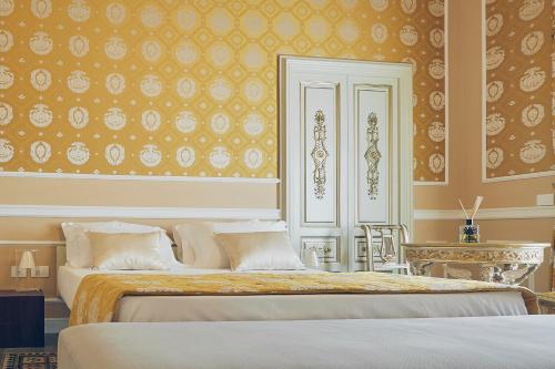 a bedroom with two beds and a wall with wallpaper at Palazzo Marletta Luxury House Hotel in Catania