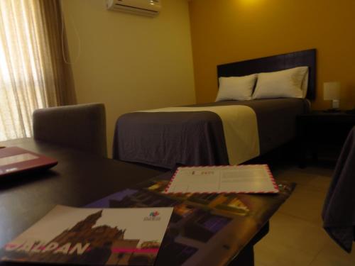 a hotel room with a bed and a table with a book at Casa Blanca Hotel in Jalpan