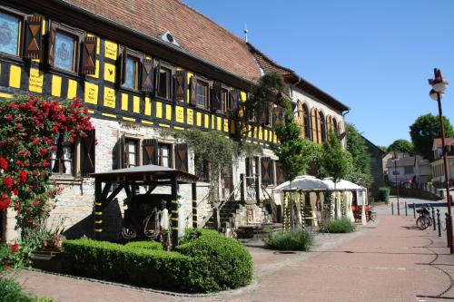 ein gelbes und weißes Gebäude mit Pflanzen darauf in der Unterkunft Gasthaus Loewenthor & Hotel Hahn in Gondelsheim