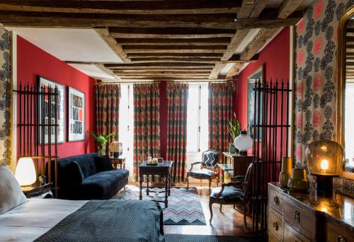a bedroom with red walls and a bed and a couch at Hôtel Le Relais Saint-Germain in Paris