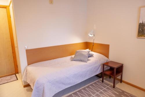 um pequeno quarto com uma cama e um candeeiro em Björnforsens Turist & Konferenshotell, Nära Husum, Örnsköldsvik em Björna