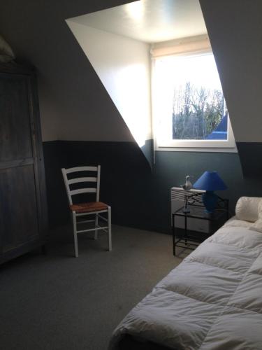 une chambre avec un lit, une chaise et une fenêtre dans l'établissement Domaine de Praline maison de Fouesnant, à Fouesnant