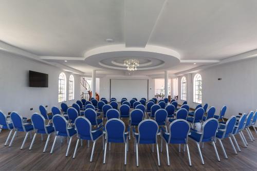 a large room with blue chairs and a screen at Comfort Gardens Sweetwaters in Nanyuki