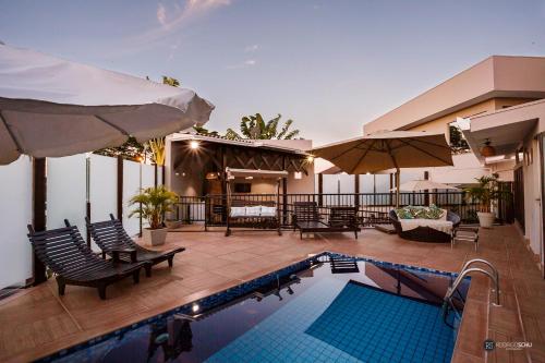 a swimming pool with chairs and umbrellas on a house at Tonello Business Hotel in Campo Mourão