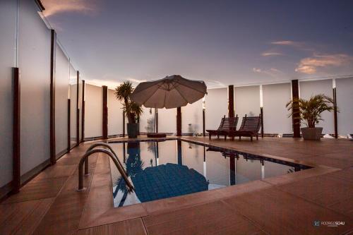 uma piscina com um guarda-sol no topo de um edifício em Tonello Business Hotel em Campo Mourão