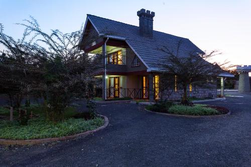 a house with a gambrel roof on a driveway at Comfort Gardens Sweetwaters in Nanyuki