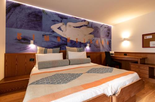a bedroom with a bed with a large painting on the wall at Hotel Isolabella Wellness in Fiera di Primiero