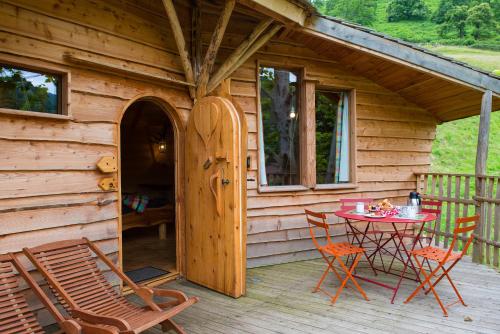 a wooden cabin with a table and chairs on a deck at Logis Hôtel Andreinia & Cabanes in Esterençuby