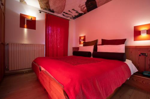a bedroom with a large red bed with red curtains at Hotel Isolabella Wellness in Fiera di Primiero