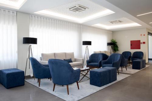 uma sala de espera com cadeiras azuis e um sofá em Mafra Hotel em Mafra