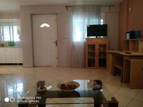 een woonkamer met een tafel, een tv en een deur bij Stavros Apartments in Artemida