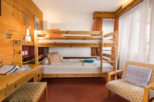1 dormitorio con 2 literas y escritorio en Hotel La Collina, en Saas-Fee
