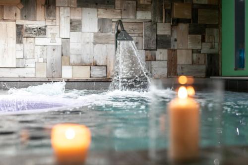 a fountain in a swimming pool with two candles at Hotel Isolabella Wellness in Fiera di Primiero