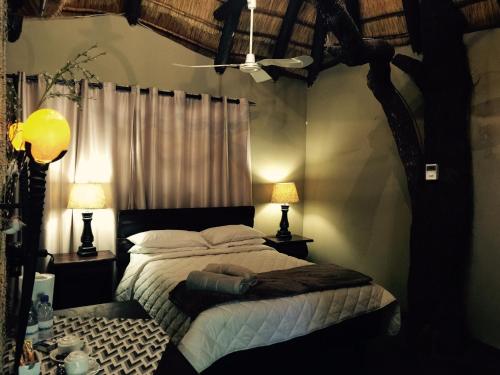 a bedroom with a bed and two lamps and a tree at Chinaka Game Lodge in Vivo