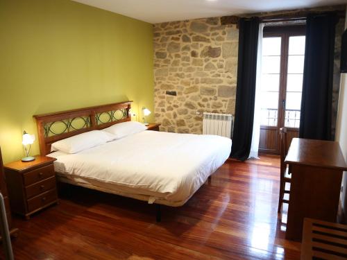 a bedroom with a bed and a stone wall at Ostatu Zegama in Zegama