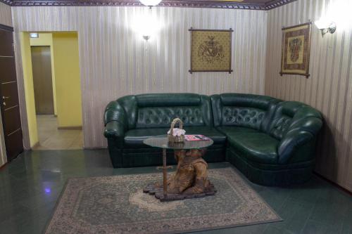 a living room with a green leather couch and a table at Britaniya in Kharkiv