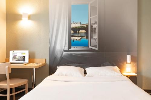a bedroom with a bed and a desk with a laptop at B&B HOTEL Laval Chang&eacute; in Chang&eacute;