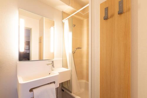 a bathroom with a sink and a mirror and a shower at B&B HOTEL Laval Changé in Changé