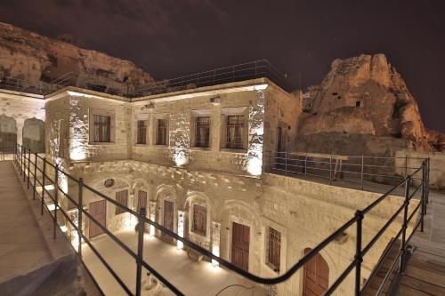 a large stone building with lights on it at night at Taru Cave Suites in Ürgüp