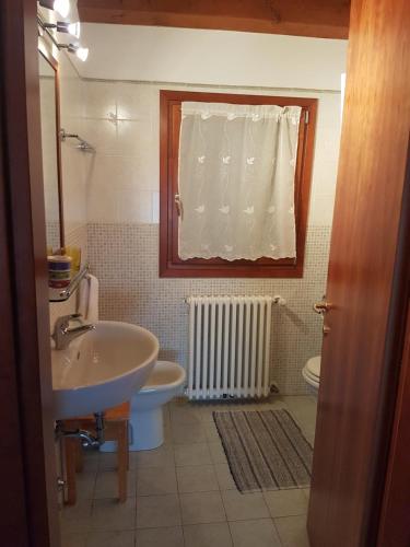 uma casa de banho com um lavatório, um WC e uma janela. em agriturismo la scuderia em Galzignano