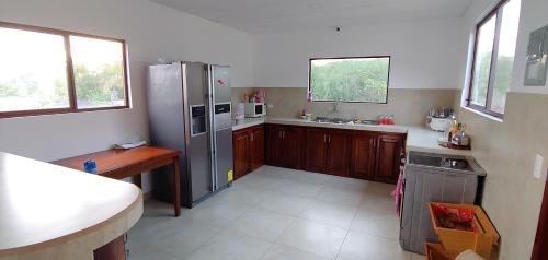 a kitchen with a stainless steel refrigerator and wooden cabinets at Hostal Punta Arena in Puerto Villamil